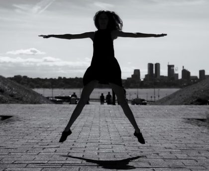 A dynamic black and white silhouette of a woman jumping with arms outstretched in Tallinn, Estonia.