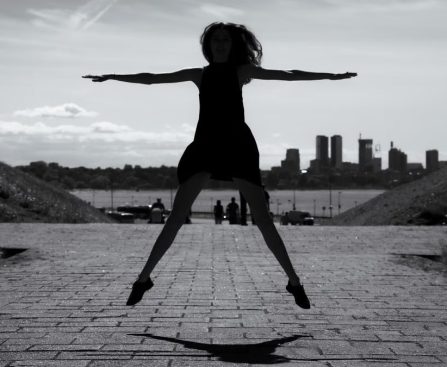 A dynamic black and white silhouette of a woman jumping with arms outstretched in Tallinn, Estonia.